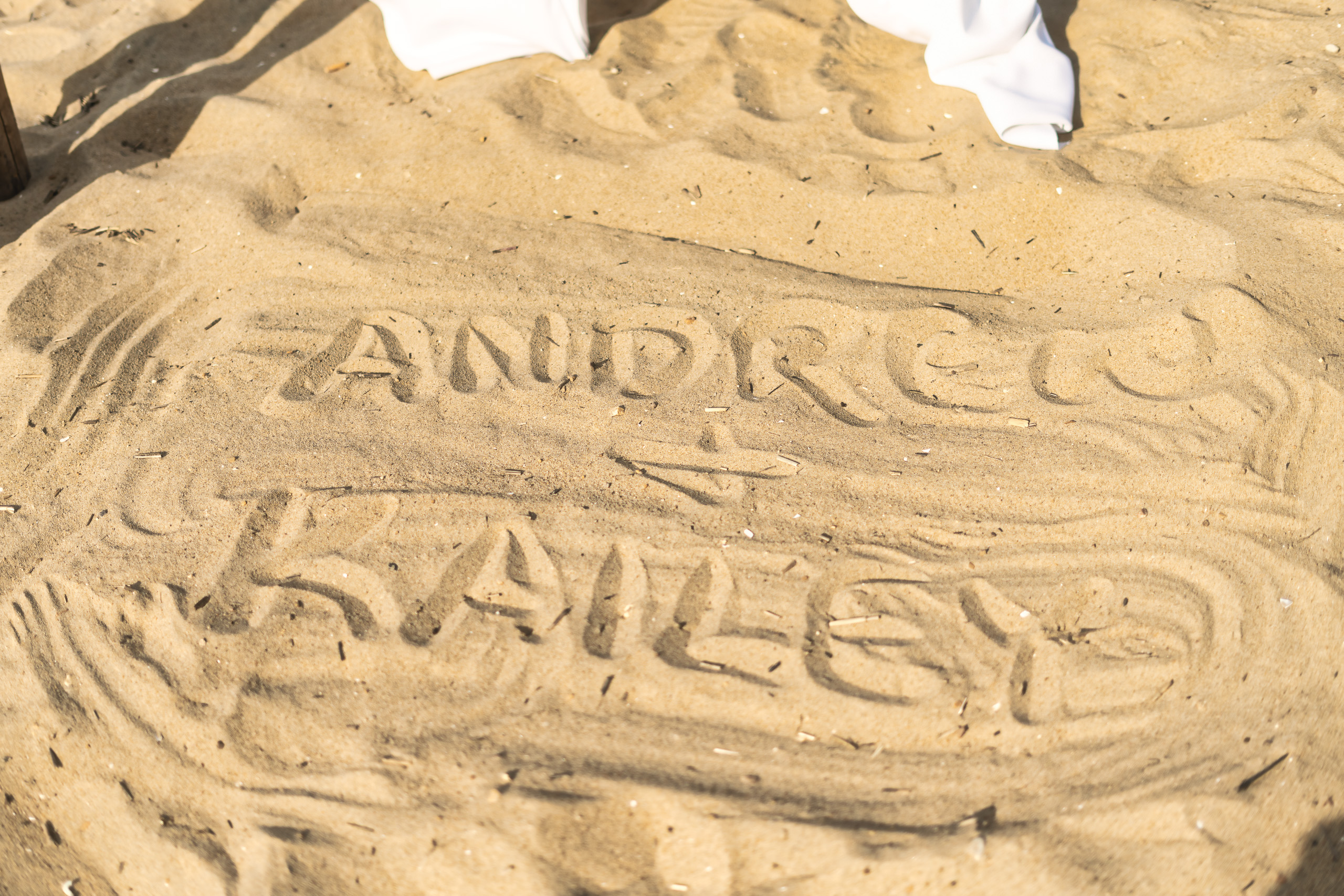 The names 'Andrew' and 'Kailey' written in the sand, with a heart symbol between them.